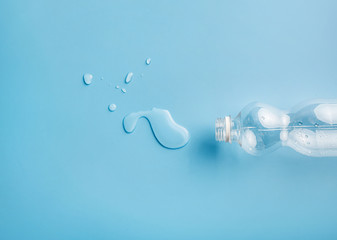 Empty plastic water bottle and water drops on blue background