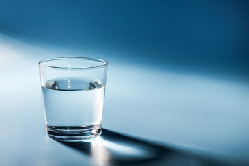 Glass of water on blue background