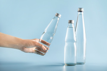 Hand choosing glass water bottle on white background