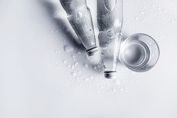 Glass water bottles and glass of water on white background