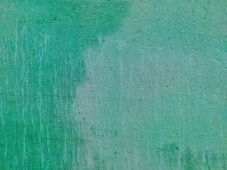 the texture of an old concrete wall is green and light green with streaks and cracks