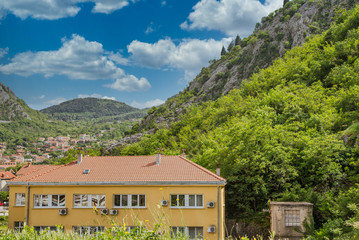 Fototapeta na wymiar A new plaster apartment building with red tile roof in green mountains of Kotor, Montenegro