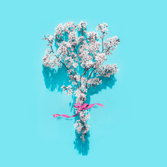 Cherry spring blossom bunch with ribbon on light turquoise background , top view. Springtime...
