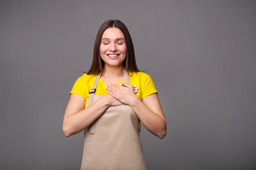 Young woman in an apron on a gray background.