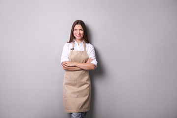 Young woman in an apron on a gray background.