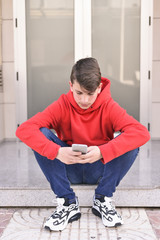 Happy young man in red clothes writing a text message to his friends with his smarthphone. concept new technologies, telecommunications