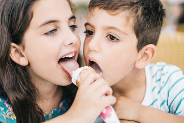 Two little kids eating an ice cream together