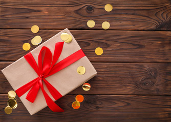 Holiday gift with red ribbons on a wooden table
