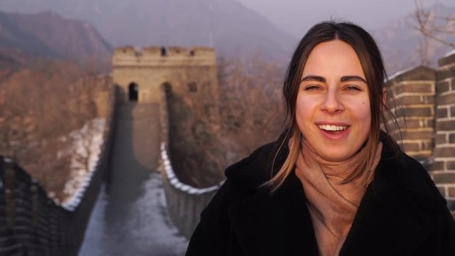Girl chews and bursts the cud on the great wall of China background