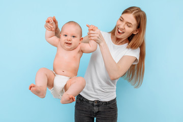 Happy cheerful mom playing with her little baby on a blue background