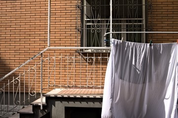 White sheets hanging on the drying rack outside the balcony (Pesaro, Italy, Europe)