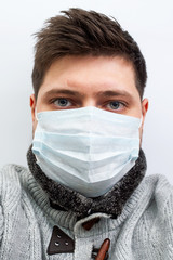 young guy caucasian in a medical mask in a sweater with bags under the eyes poor view. coronavirus covid 2019, quarantine