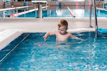Naklejka premium cute toddler kid looking at rubber toy in swimming pool