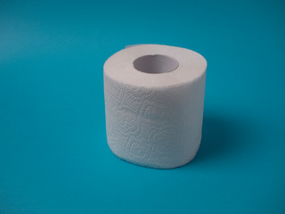 A white perforated two-layer toilet paper roll isolated on a blue background close-up with copy space.
