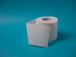 A white perforated two-layer toilet paper roll isolated on a blue background close-up with copy space.