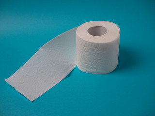 A white perforated two-layer toilet paper roll isolated on a blue background close-up with copy space.
