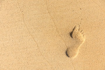 Fototapeta na wymiar Huella de un pie sobre la arena de la playa