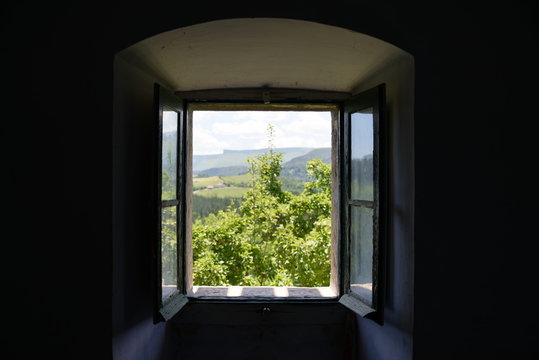 Vista de un paisaje campestre a trav&eacute;s de la ventana de una casa antigua