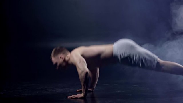 muscular man doing push ups on black with smoke