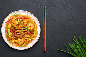 Singapore Mei Fun in white plate on dark slate background. Singapore Noodles is chinese cuisine...