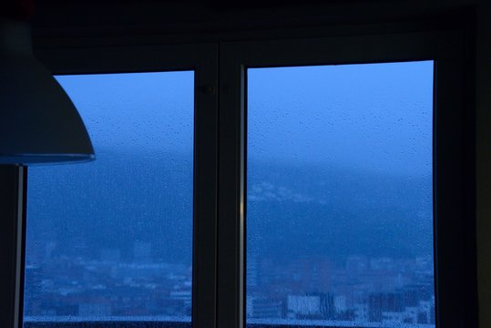 Picture Of A Rainy Blue Day Through The Window From Inside A Dark House