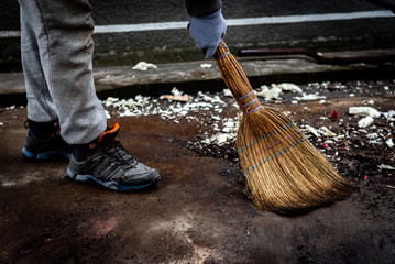 A woman sweeps the trash. Cleaning the area from garbage in the yard outdoor.