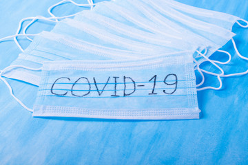 Medical mask with COVID-19 written on it against the blue background