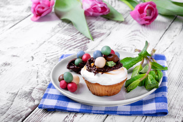 Easter cupcake topped with multicolored marzipan eggs, chocolate nest and marshmallow creme