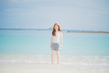 Fototapeta na wymiar 沖縄の海と麦わら帽子のロングヘアの女性