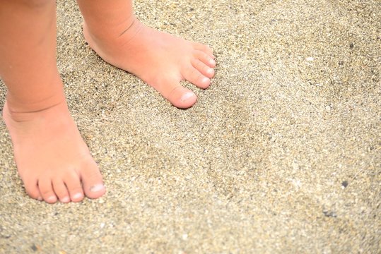 Pies de niño en la arena de la playa