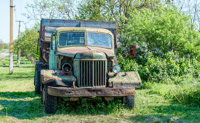 Old rusty truck on the green spring rural field