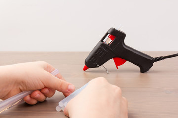 Glue gun in the child's hand. Кid glues with a glue gun. closeup