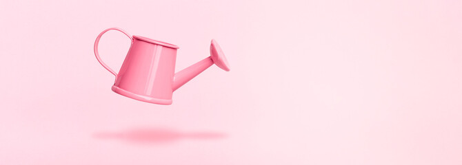 levitating watering can on pink background, concept gardening accessories, panoramic mock-up