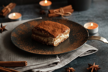 Tiramisu cake on a plate. Romantic composition with candles and other elements
