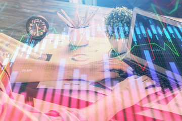 Double exposure of stock graph with businessman typing on computer in office on background. Concept...