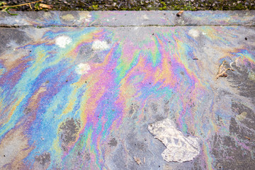 The iridescent rainbow colours of spilt oil n a dirty path