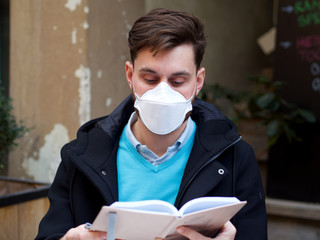Worried man wearing FFP3 face protection mask in city center, doing regular stuff, using his phone.
