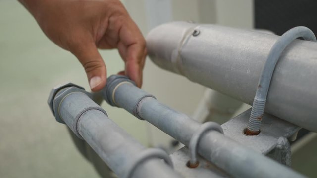 Hand close-up of serviceman to tighten a screw of electric conduit