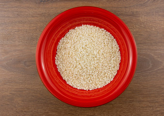 Rice in a red bowl on a wooden background. Top view