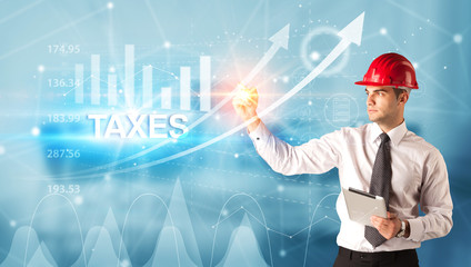 Young businessman with helmet drawing TAXES inscription, modern business technology concept