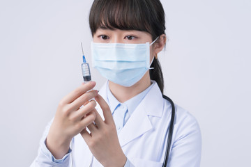 Doctor holding syringe with face mask, concept of young female physician injects coronavirus, COVID-19 vaccine on white background, close up, copy space