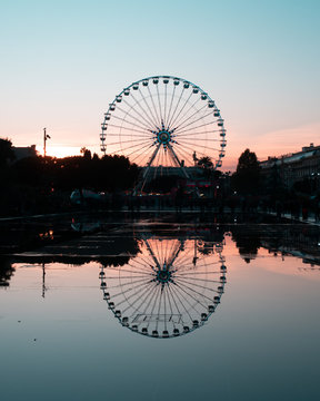 silhouette of ferris wheel at sunset or sunrise & water reflection