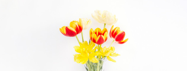 Tulip flower in glass vase with picture frame place on white wooden table background against clean wall at home, close up, Mother's Day decor concept.