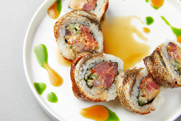 Sushi Uramaki with salmon, green algae, rolls poured with sauce wrapped in fish and, with spices