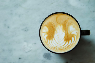 Latte in black cup on stone background 