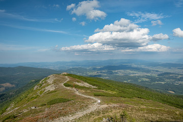 A tourist path on the top a mountain with an open view over hills and valleys and tourist walking...