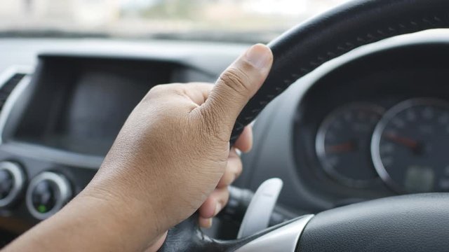 The hand of the driver holding the steering wheel