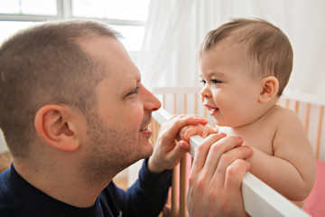 father look infant daughter into baby crib