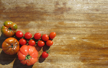 Tomatoes illuminated by bright sunlight on an old wooden table. Healthy food. Copy space.