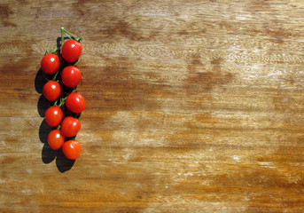 Tomatoes-cherry illuminated by bright sunlight on an old wooden table. Healthy food. Copy space.